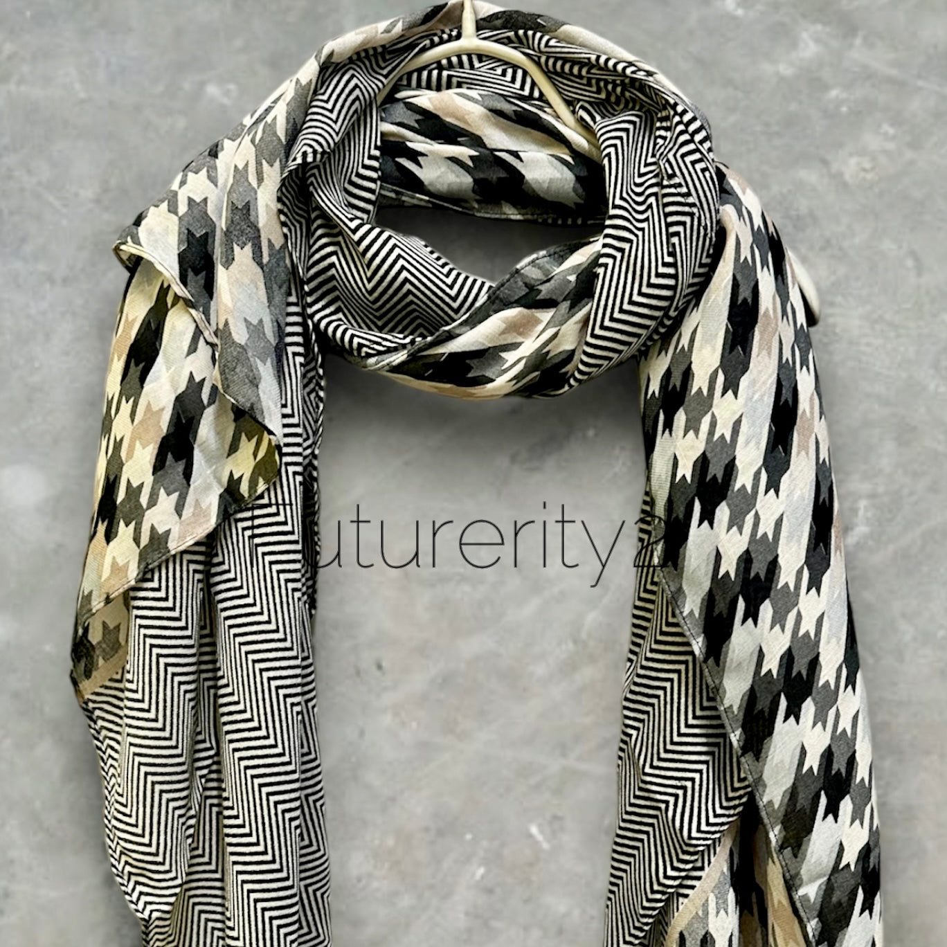 A black and white patterned scarf with a chevron pattern on one side and a houndstooth pattern on the other side.