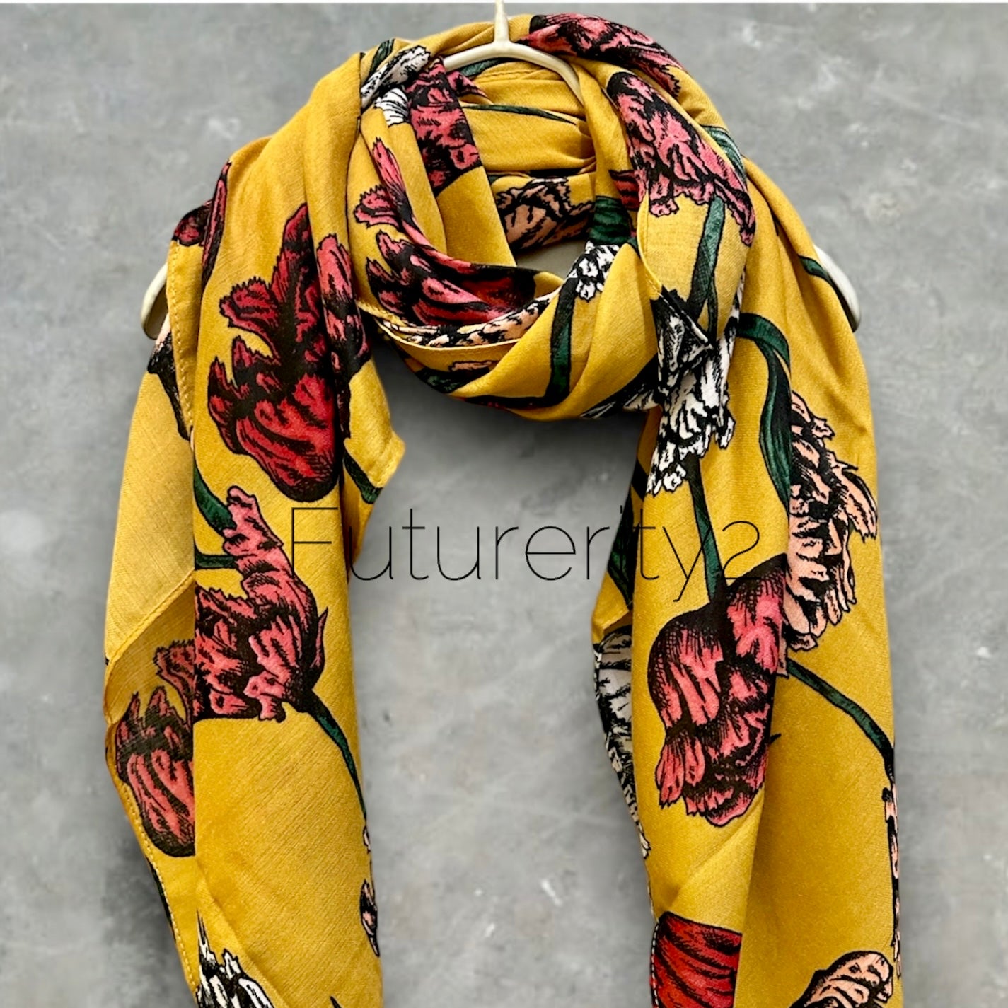 A yellow floral scarf with pink, red, and white flowers. The scarf is made of a soft, silky fabric and has a flowing design.