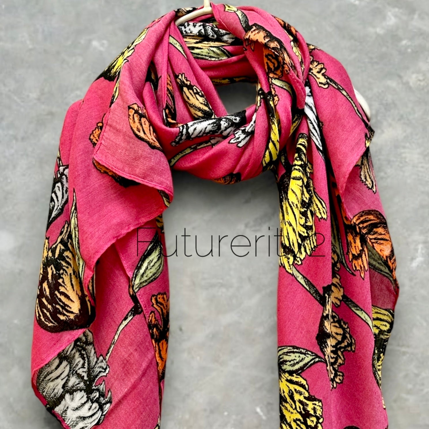 A pink floral scarf with yellow, orange, and black flowers. The scarf is made of a soft, lightweight fabric and has a fringed edge.