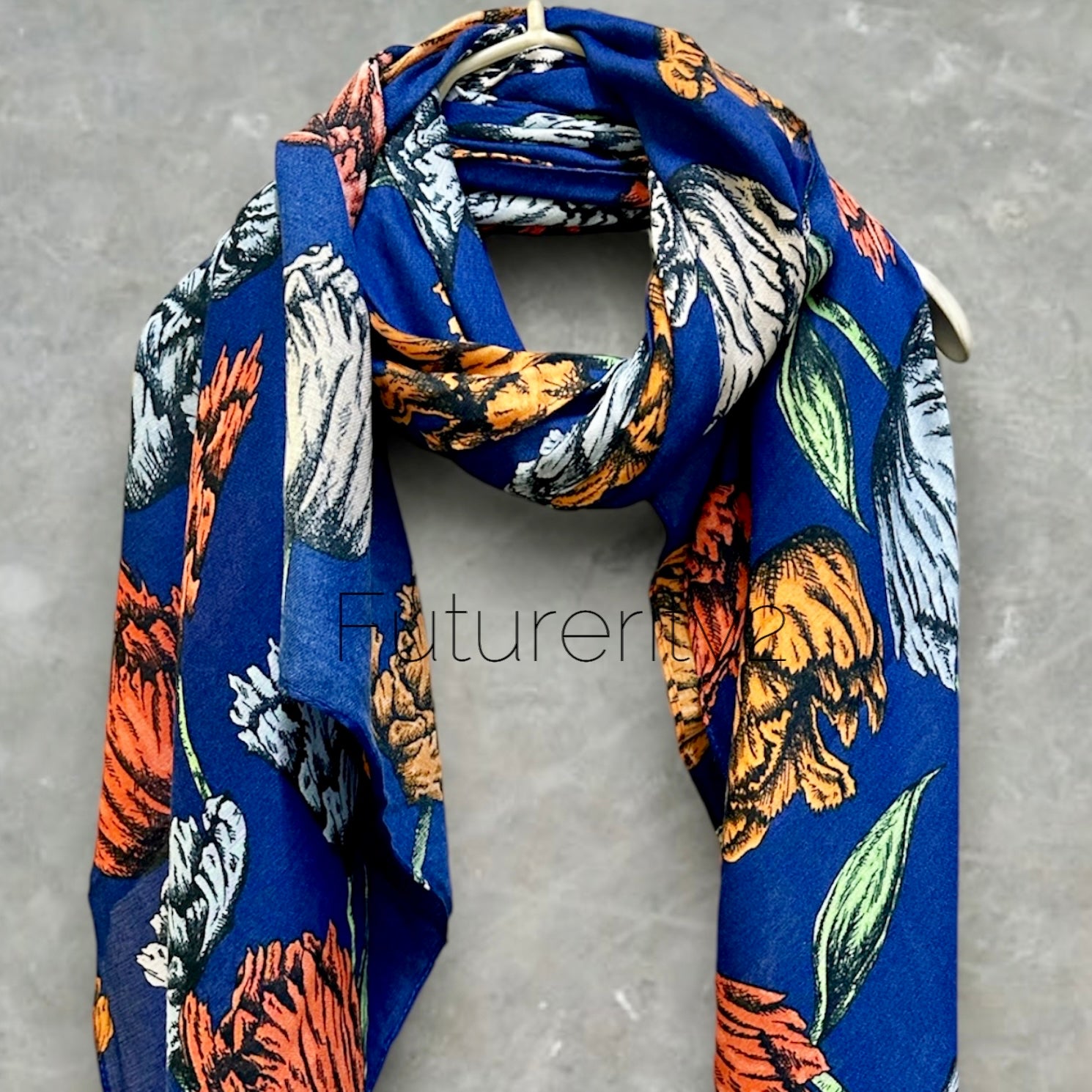A blue scarf with a floral print. The flowers are orange, yellow, and white. The scarf is made of a soft, lightweight fabric.