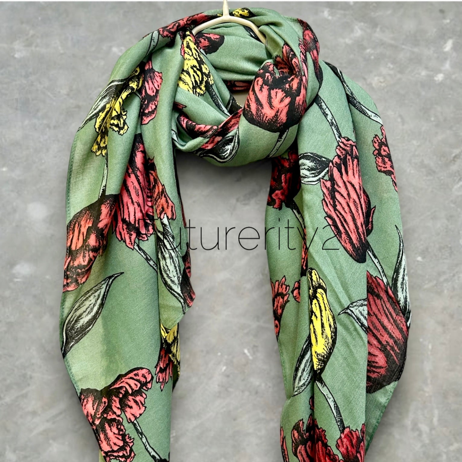 A green floral scarf with a pattern of pink, yellow, and black flowers. The scarf is made of a soft, lightweight fabric and is perfect for adding a touch of color to any outfit.
