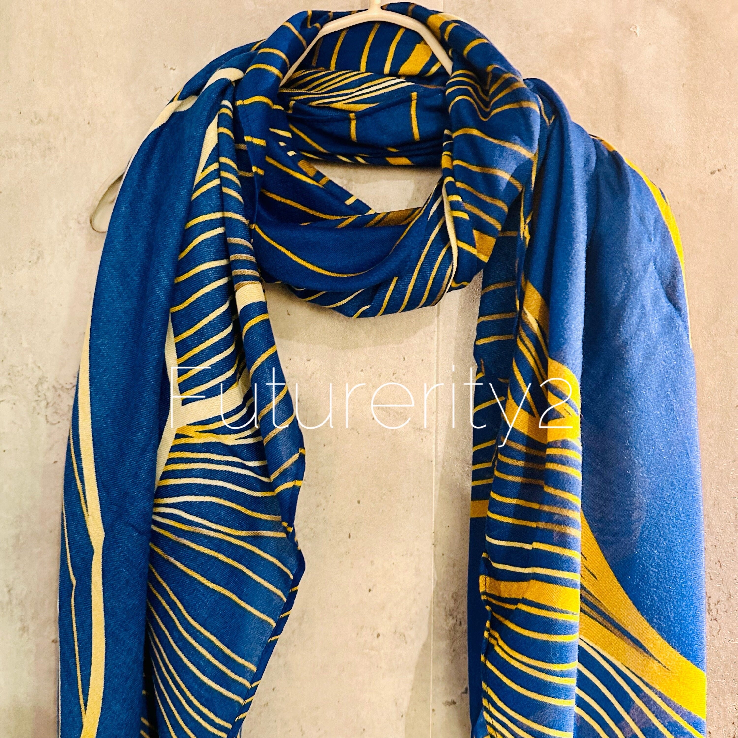 A blue and gold scarf with a striped pattern. The scarf is made of a soft, lightweight fabric and has a fringed edge.