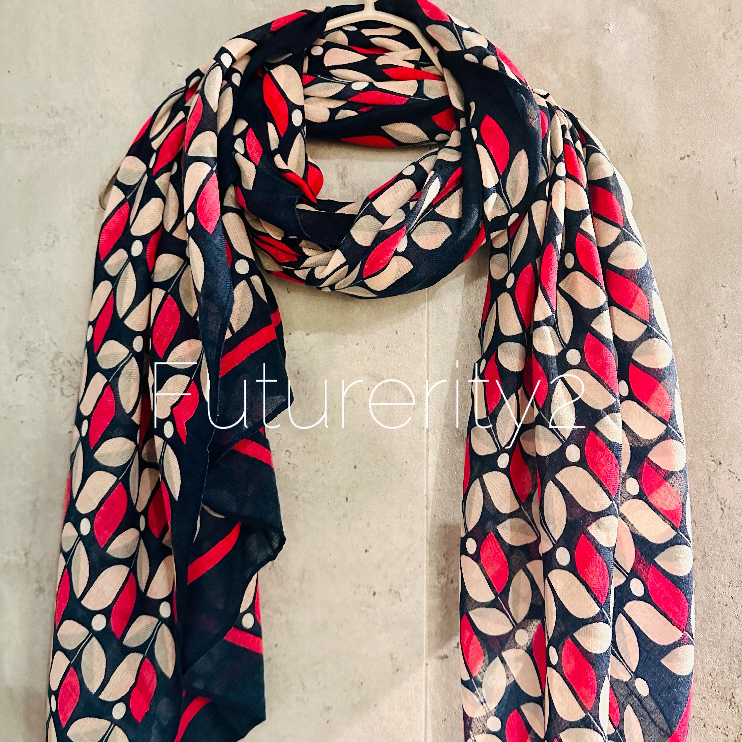 A black and white patterned scarf with pink accents. The scarf has a leaf design and is made of a soft, lightweight fabric.