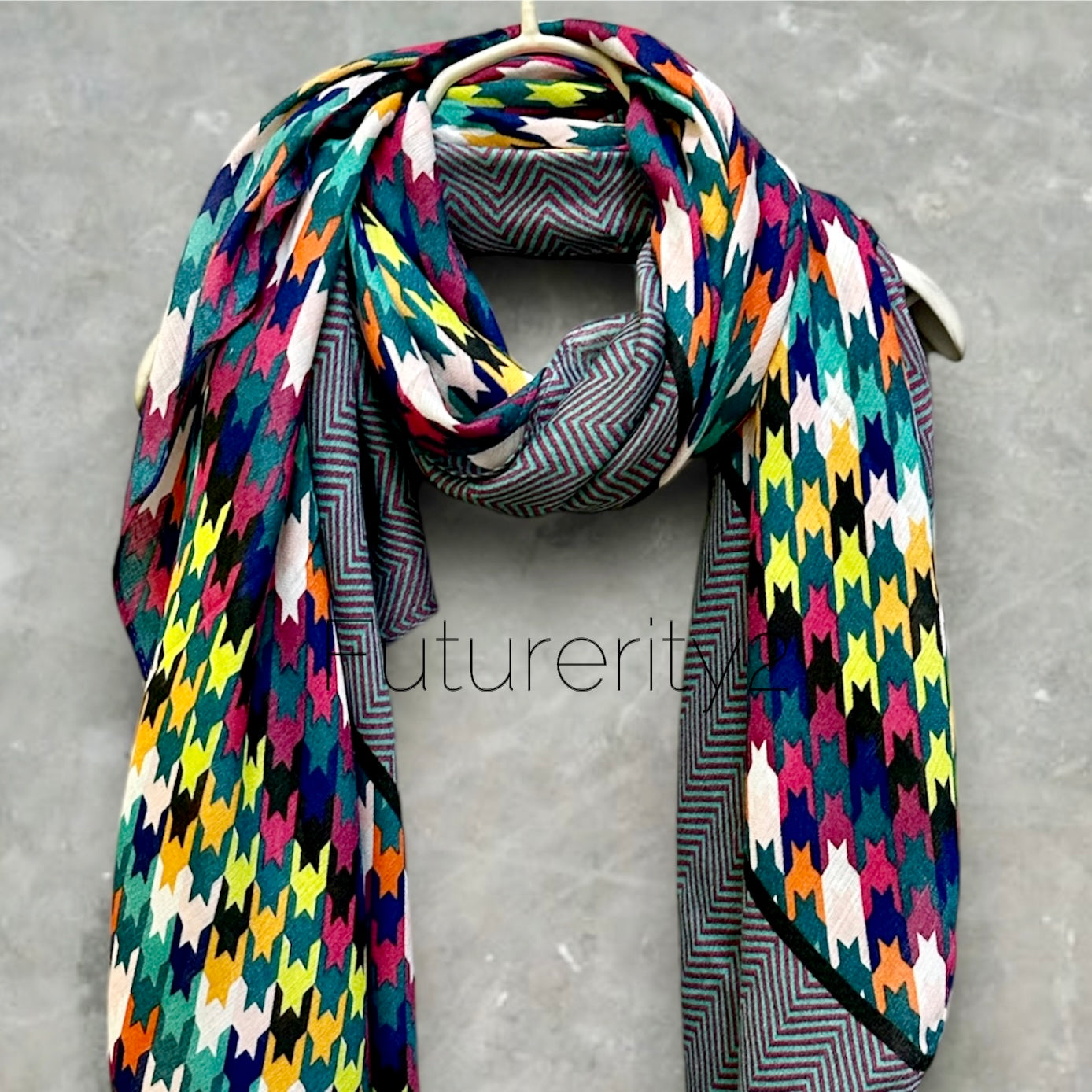 A colorful scarf with a geometric pattern. The scarf is made of a soft, lightweight fabric and has a reversible design. One side of the scarf features a zig-zag pattern in shades of blue, green, and white. The other side of the scarf features a houndstooth pattern in shades of pink, yellow, blue, and green.