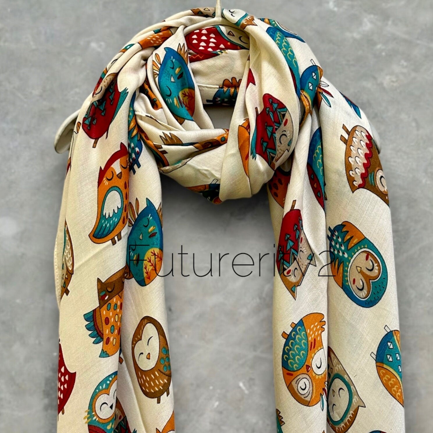 A off white scarf with a repeating pattern of colorful owls. The owls are in various poses and have different designs. The scarf is made of a soft, lightweight fabric and is perfect for adding a touch of whimsy to any outfit.
