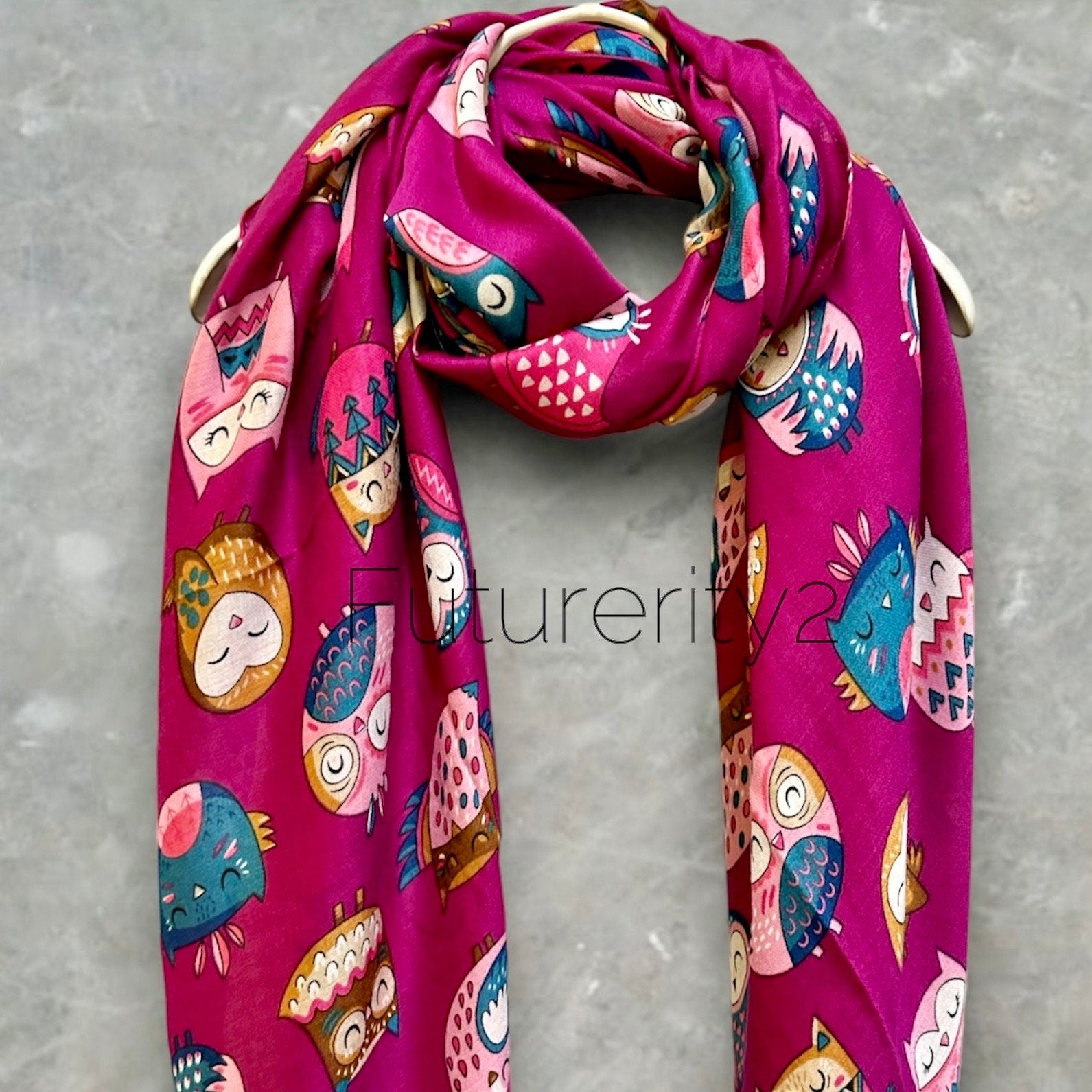 A pink scarf with a repeating pattern of colorful owls. The owls are in various poses and have different designs. The scarf is made of a soft, lightweight fabric and is perfect for adding a touch of whimsy to any outfit.